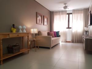 ein Wohnzimmer mit einem Sofa und einem Fenster in der Unterkunft Maceio Facilities Apartamento Temporada in Maceió