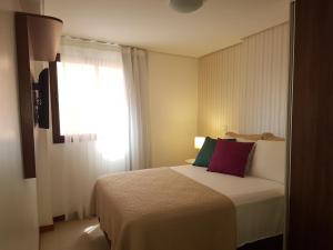 Habitación de hotel con cama y ventana en Maceio Facilities Apartamento Temporada en Maceió