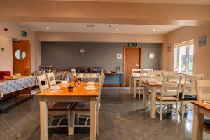 una sala da pranzo con tavoli e sedie in legno di Aran Walkers Lodge a Inis Mor