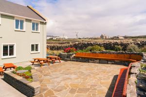 a patio with benches and tables next to a house at Aran Walkers Lodge in Inis Mor