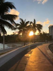 a street with palm trees and the sun setting at Villa Domenico in Salvador