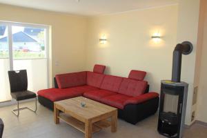 a living room with a red couch and a fireplace at Ferienhaus Sinha_SOMM in Ostseebad Karlshagen