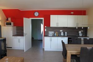 een keuken met witte kasten en een rode muur bij Ferienhaus Sinha_SOMM in Ostseebad Karlshagen