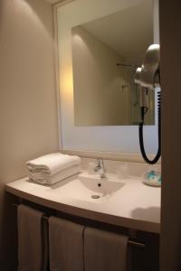 y baño con lavabo, espejo y toallas. en ibis Styles Chinon, en Chinon