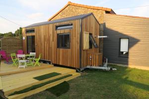 una casa pequeña con terraza y mesa en Tiny House à 30 min du Puy du Fou jusqu'à 6 personnes, en Yzernay