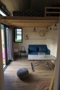 sala de estar con sofá azul y mesa en Tiny House à 30 min du Puy du Fou jusqu'à 6 personnes, en Yzernay