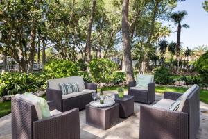 un patio avec des chaises, des tables et des arbres dans l'établissement El Oasis Villa Resort, à L'Eliana
