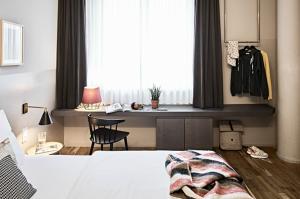 a room with a bed, chair, and a window at Bold Hotel München Giesing in Munich
