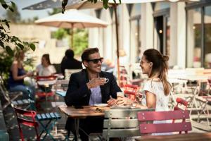 um homem e uma mulher sentados numa mesa num restaurante ao ar livre em Bold Hotel München Giesing em Munique