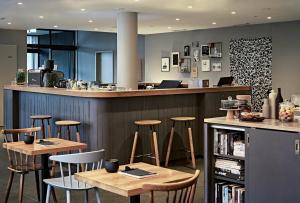 a bar with chairs and tables in a restaurant at Bold Hotel München Giesing in Munich