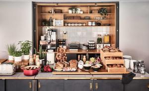 a kitchen with a counter with food on it at Bold Hotel München Giesing in Munich