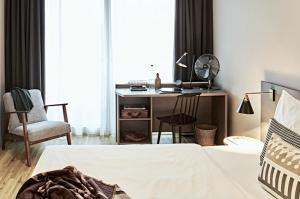 a room with a bed, chair, desk and a lamp at Bold Hotel München Zentrum in Munich