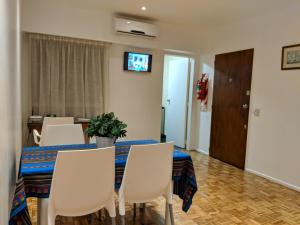 Apartamento Edificio Crucero في بوينس آيرس: غرفة طعام مع طاولة وكراسي وتلفزيون