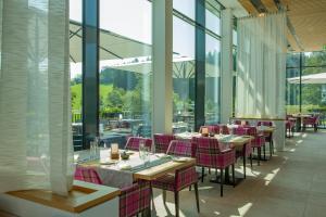 een eetkamer met tafels, stoelen en ramen bij Hotel Edita in Scheidegg