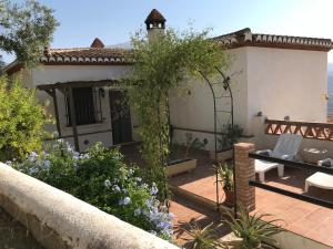a house with a patio with a table and a garden at Jardin Andaluz Appart Alhambra in Pinos del Valle