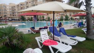 een groep stoelen en parasols naast een zwembad bij Folla Residence Apartments in El Ahmar