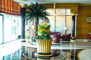a lobby with a large vase with flowers in it at Ewan Hotel Sharjah in Sharjah