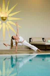 a woman doing a yoga pose next to a pool at Anassa in Polis Chrysochous