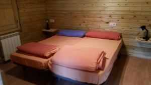 two twin beds in a room with wooden walls at Alojamiento Rural Cabuerniaventura in Ruente