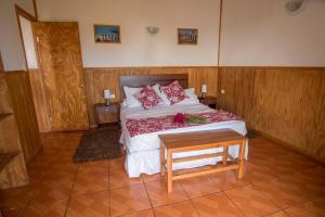 a bedroom with a bed with red pillows and a table at Cabañas Henua Iti in Hanga Roa