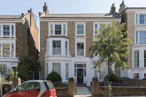 ロンドンにあるBright Clapham flat with private garden, sleeps 4の家の前に停車した赤い車