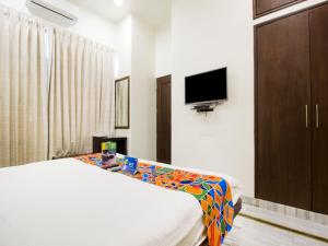 - une chambre avec un lit et une télévision à écran plat dans l'établissement FabHotel Jaipur Villa, à Jaipur