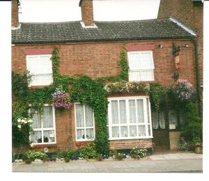 a brick house with white windows and flowers at Compton House in Ashbourne