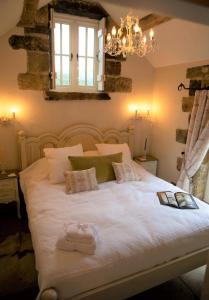 a bedroom with a large white bed with a chandelier at Bluebells Cottage in Chop Gate