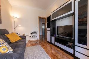 a living room with a couch and a flat screen tv at Like-home Casa Campolide in Lisbon