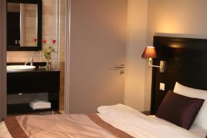 a bedroom with a bed and a sink and a mirror at La Place Boutique Hotel in Antibes