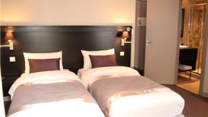 two beds in a room with a black headboard at La Place Boutique Hotel in Antibes