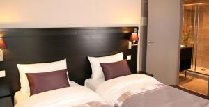 a bedroom with a black headboard and two white beds at La Place Boutique Hotel in Antibes