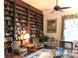 biblioteca con estanterías, mesa y sillas en Historic Michabelle Inn, en Hammond
