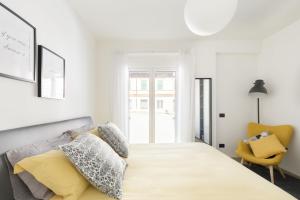 a white bedroom with a large bed and a yellow chair at Casa Scalzi in Rome