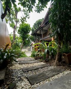 a garden with rocks and a house in the background at Sarah Guest House in Chiang Mai