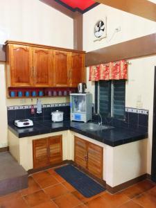 une cuisine avec des placards en bois et un comptoir noir dans l'établissement Fully AC 3BR House for 8pax near Airport and SM with 100mbps Wifi, à Puerto Princesa