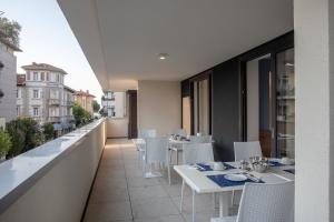 Aparthotel Miramare في غرادو: شرفة بطاولات بيضاء وكراسي على مبنى
