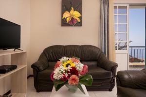 a living room with a couch with a bouquet of flowers at Casa do Miradouro in Ponta do Sol