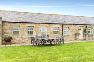 a table and chairs in front of a stone building at Beach View, Waterside Cottages in Alnmouth