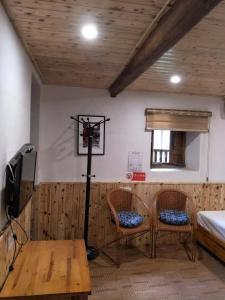 a room with two chairs and a table and a television at Nanjing Tulou Qingdelou Inn in Nanjing