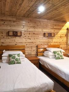 Duas camas num quarto com paredes de madeira em Nanjing Tulou Qingdelou Inn em Nanjing