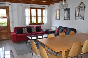 sala de estar con mesa y sofá rojo en Chalet Los Ibones - Lodge Escarrilla, en Escarrilla