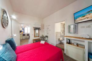 una camera con letto rosso e TV di Bed & Breakfast ALBA a Capoterra