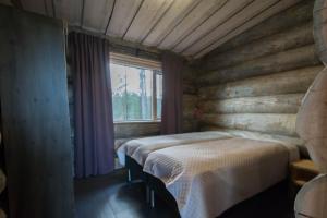 two beds in a room with a window at Villa Konttaisenranta in Ruka