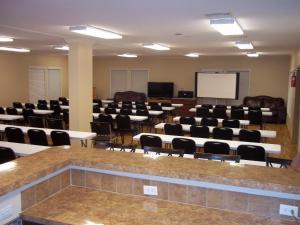a conference room with tables and chairs and a screen at Village Lodge in Ruidoso