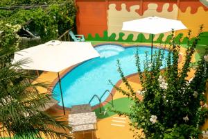 a swimming pool with two umbrellas and a slide at Hotel Boutique La Casa de las Flores in Cahuita