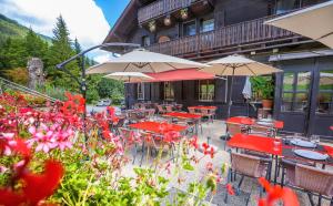un patio esterno con tavoli, ombrelloni e fiori di Guest House du Grand Paradis - On Piste a Champéry