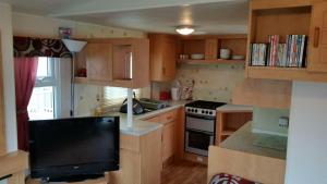 a small kitchen with wooden cabinets and a television at Silver beach in Ingoldmells