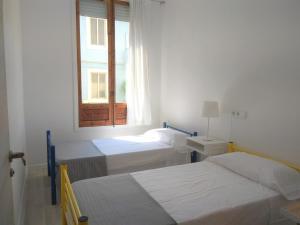 Habitación blanca con 2 camas y ventana en Disfruta - Enjoy Valencia Ruzafa, en Valencia