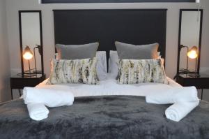 una cama grande con sábanas y almohadas blancas en Columbine Place, en Durbanville